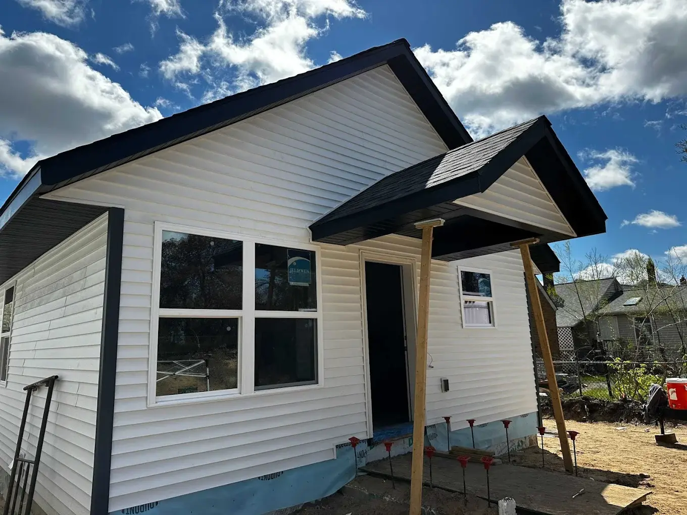 Near-complete DADU exterior with white siding, dark roof, and covered entry porch