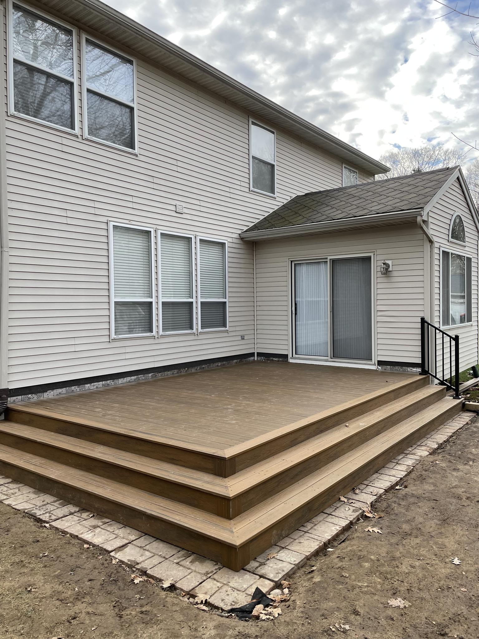 Wide-angle view of completed composite deck with steps and paver walkway