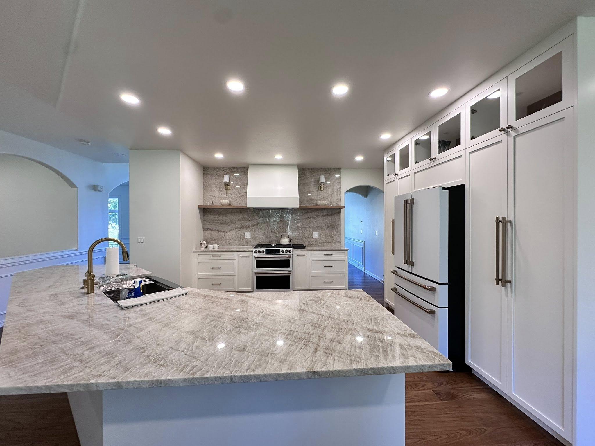 Open concept kitchen remodel with marble countertop island, recessed lighting, and stone backsplash in Snohomish County