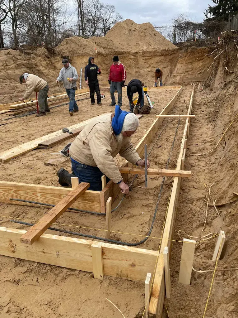 Construction crew building concrete footing forms for retaining wall foundation