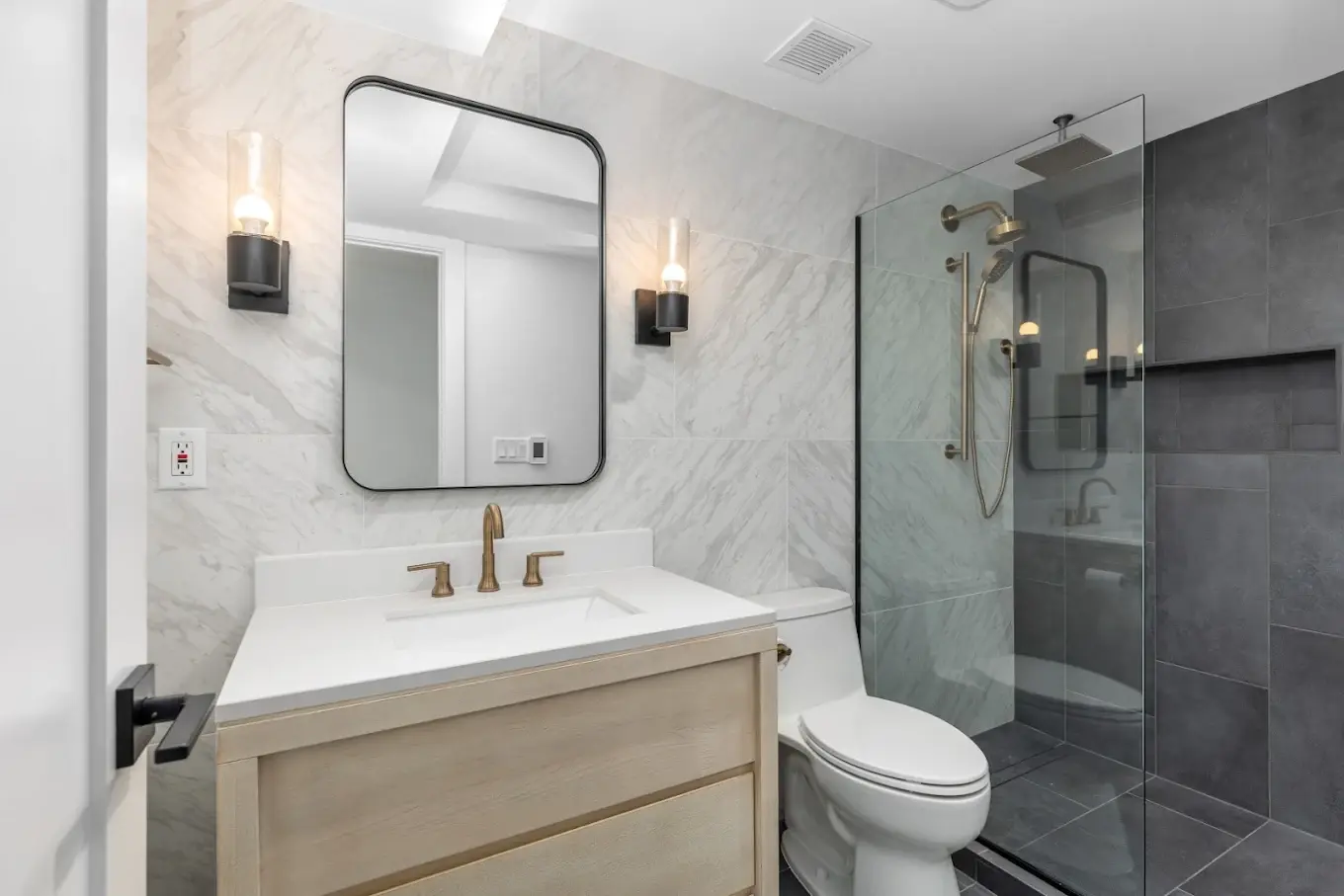 Bright bathroom vanity with black fixtures and stone countertop