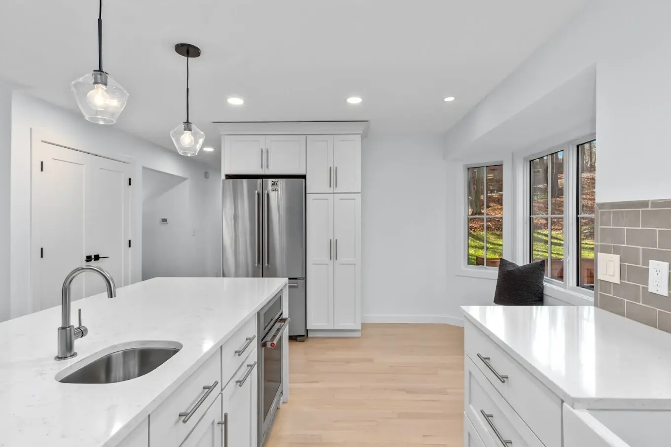 Bright kitchen with white cabinetry, quartz island, and pendant lighting